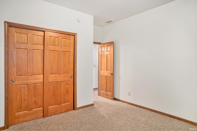 unfurnished bedroom featuring light carpet and a closet