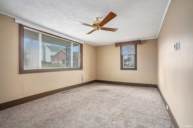 empty room with ceiling fan, carpet floors, a textured ceiling, and ornamental molding