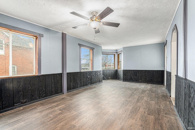 empty room with a textured ceiling, ceiling fan, and dark wood-type flooring