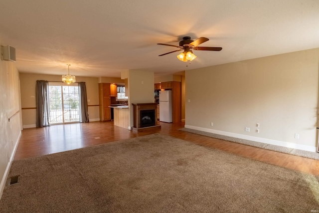 unfurnished living room with hardwood / wood-style floors and ceiling fan with notable chandelier