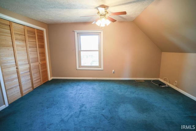 additional living space featuring a textured ceiling, dark carpet, and lofted ceiling