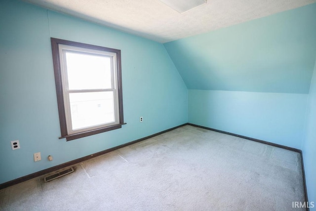 bonus room featuring a textured ceiling, light colored carpet, and lofted ceiling