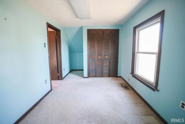 unfurnished bedroom with a closet, multiple windows, and light colored carpet