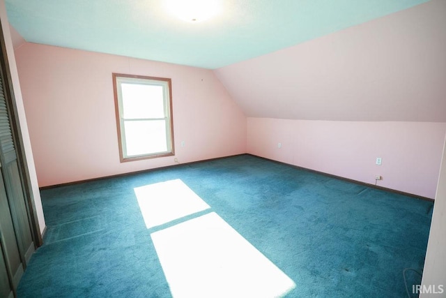 additional living space with dark carpet and lofted ceiling