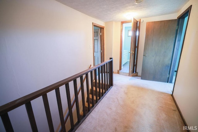 hallway with light carpet and a textured ceiling