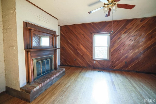 unfurnished living room with wooden walls, ceiling fan, and hardwood / wood-style flooring