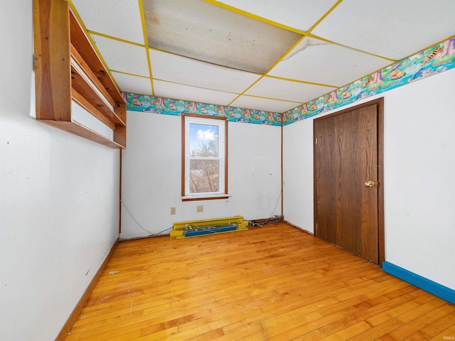 unfurnished room featuring wood-type flooring and a paneled ceiling