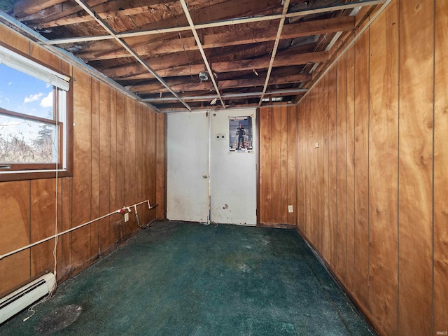 basement featuring wood walls, dark carpet, and a baseboard heating unit