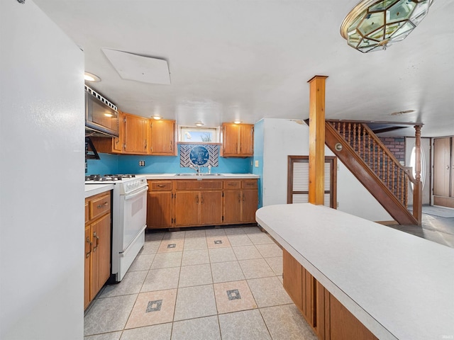 kitchen with light tile patterned flooring, sink, and gas range gas stove