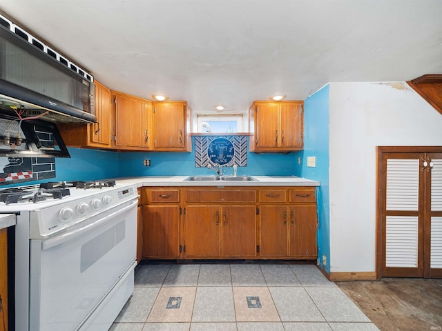 kitchen featuring light tile patterned flooring, white range with gas stovetop, sink, and extractor fan