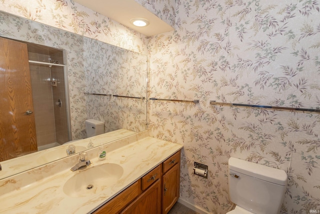 bathroom featuring a shower with door, vanity, and toilet