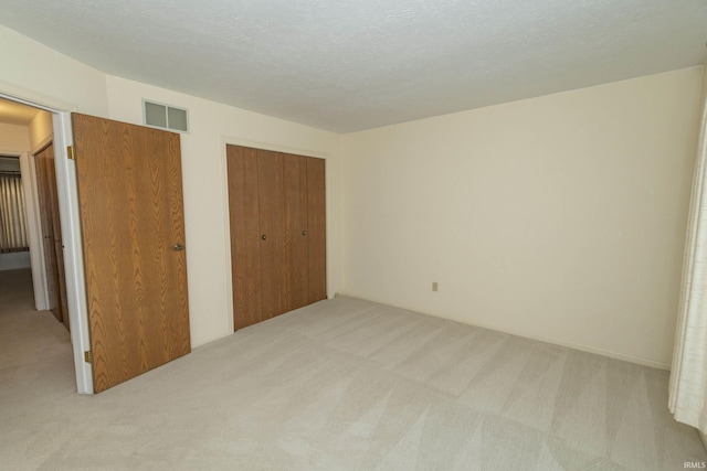 unfurnished bedroom with light colored carpet and a textured ceiling