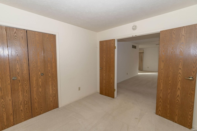 unfurnished bedroom with light carpet and a closet