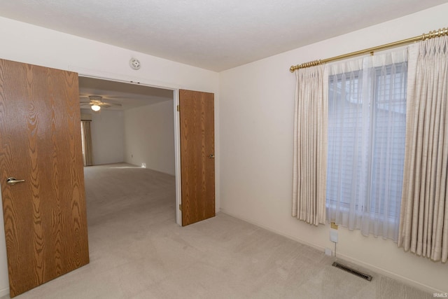 spare room with ceiling fan and light colored carpet