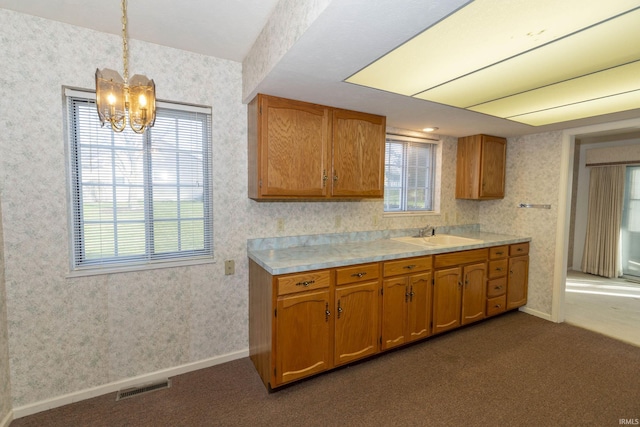 kitchen featuring plenty of natural light, hanging light fixtures, a notable chandelier, and dark colored carpet