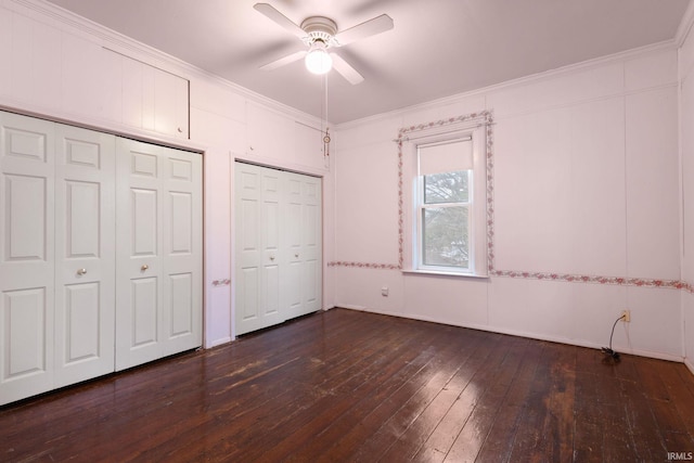 unfurnished bedroom with multiple closets, ceiling fan, crown molding, and dark wood-type flooring