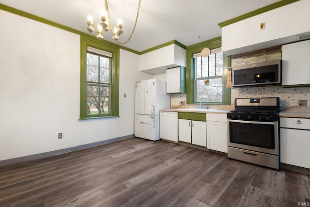 kitchen with dark hardwood / wood-style flooring, backsplash, stainless steel appliances, an inviting chandelier, and white cabinetry