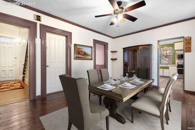 dining area featuring crown molding, dark hardwood / wood-style flooring, and ceiling fan with notable chandelier