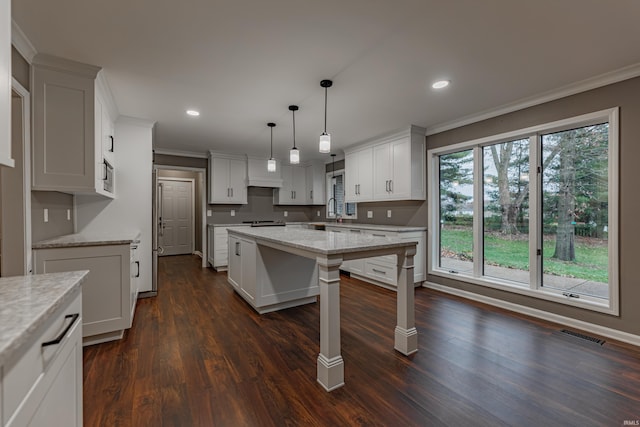 kitchen with dark hardwood / wood-style flooring, white cabinets, decorative light fixtures, and a kitchen island