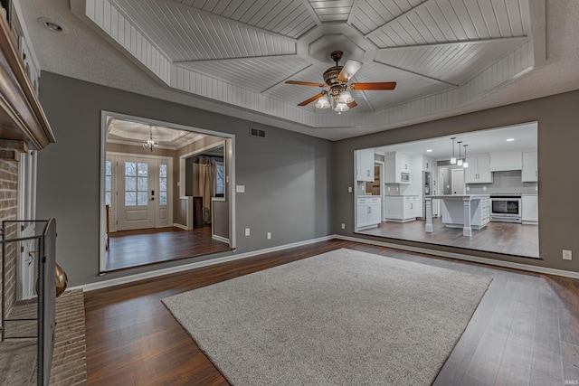 unfurnished living room with ceiling fan with notable chandelier, dark hardwood / wood-style floors, a raised ceiling, and wooden ceiling