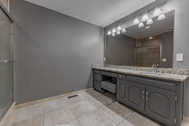 bathroom featuring vanity, a textured ceiling, tile patterned floors, and a shower with shower door