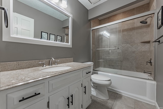 full bathroom with vanity, tile patterned floors, bath / shower combo with glass door, toilet, and a textured ceiling