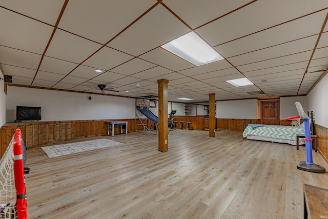 playroom featuring light hardwood / wood-style floors, a drop ceiling, and wood walls