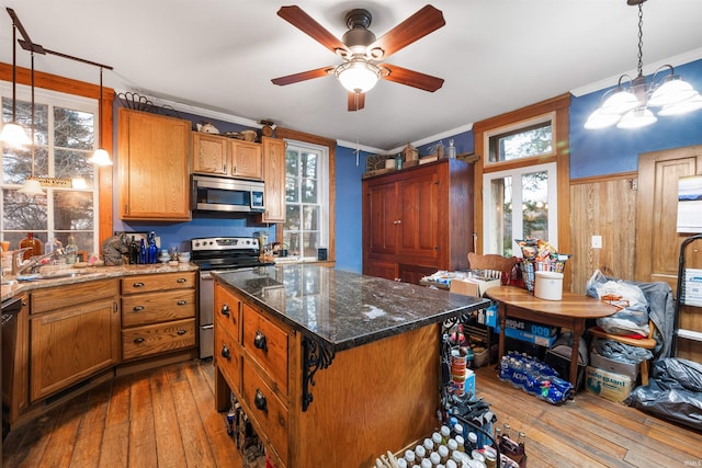 kitchen featuring hanging light fixtures, sink, light wood-type flooring, appliances with stainless steel finishes, and a kitchen island