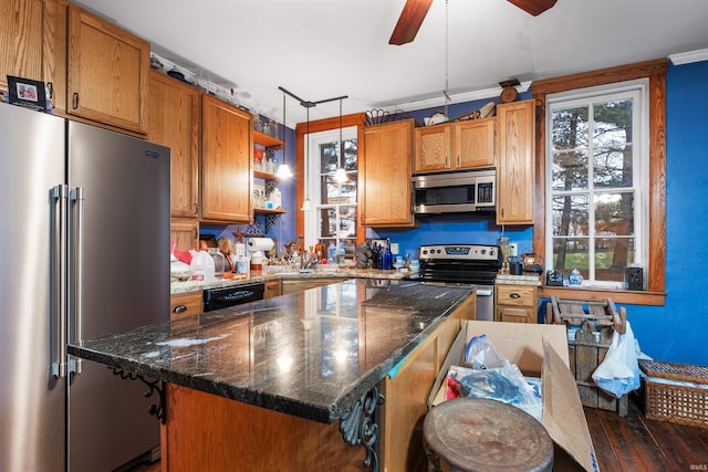 kitchen with ceiling fan, dark wood-type flooring, stainless steel appliances, dark stone counters, and pendant lighting