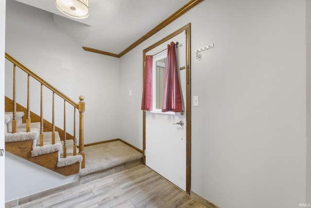 foyer entrance with crown molding and light hardwood / wood-style flooring