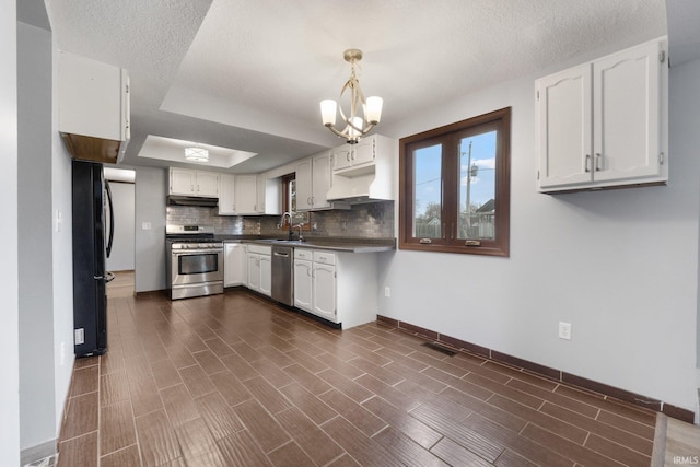 kitchen featuring white cabinets, appliances with stainless steel finishes, decorative light fixtures, and sink