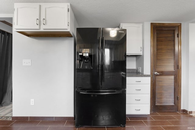 kitchen with white cabinetry, black refrigerator with ice dispenser, and a textured ceiling