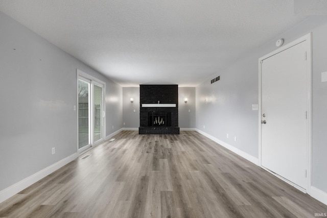 unfurnished living room featuring a fireplace, light hardwood / wood-style flooring, and a textured ceiling