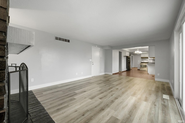 unfurnished living room with light hardwood / wood-style floors and a notable chandelier