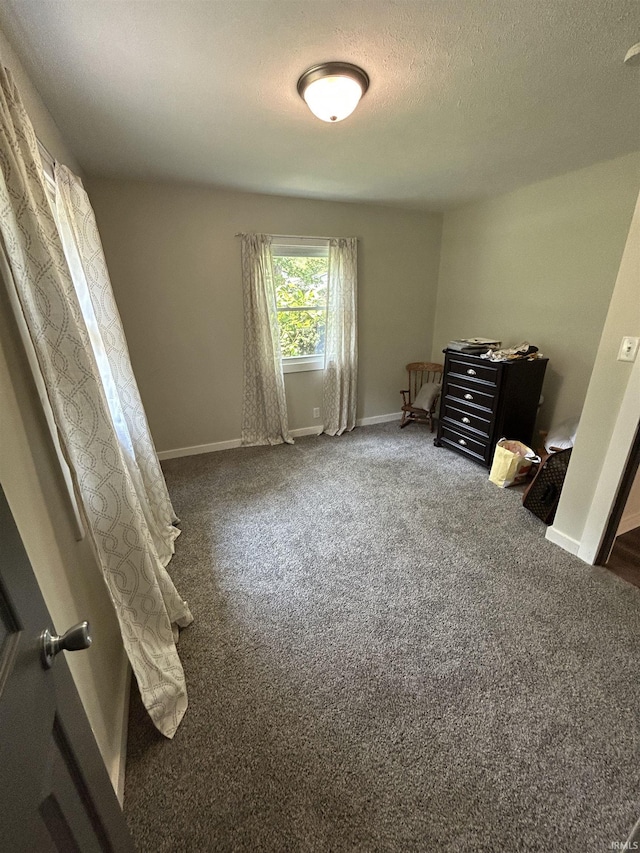 unfurnished bedroom with a textured ceiling and dark colored carpet