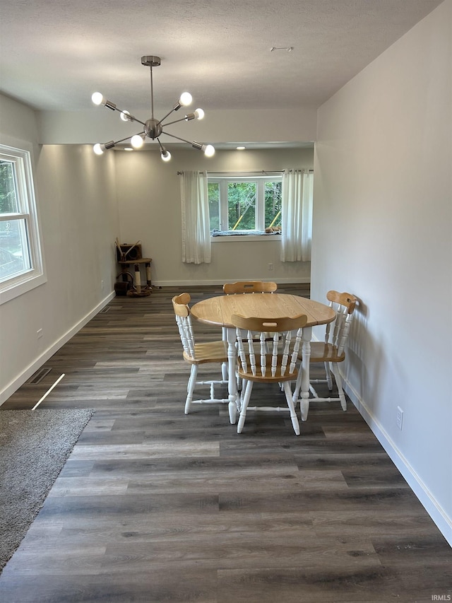 dining area featuring a textured ceiling, an inviting chandelier, and dark wood-type flooring