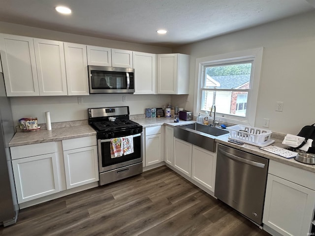 kitchen with dark hardwood / wood-style flooring, white cabinetry, sink, and appliances with stainless steel finishes