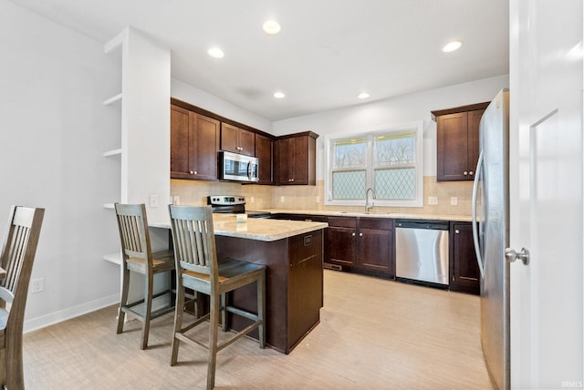 kitchen featuring sink, a kitchen bar, stainless steel appliances, and tasteful backsplash