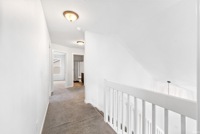 corridor featuring light colored carpet and lofted ceiling