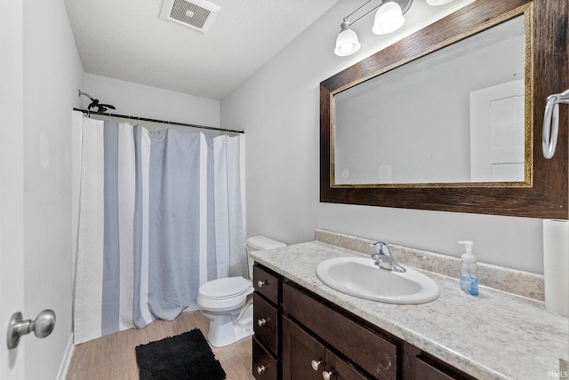 bathroom featuring walk in shower, hardwood / wood-style floors, a textured ceiling, toilet, and vanity