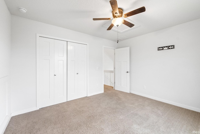 unfurnished bedroom featuring ceiling fan, a closet, light carpet, and a textured ceiling