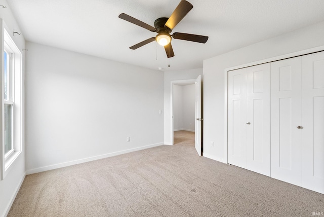 unfurnished bedroom with ceiling fan, light carpet, and a closet