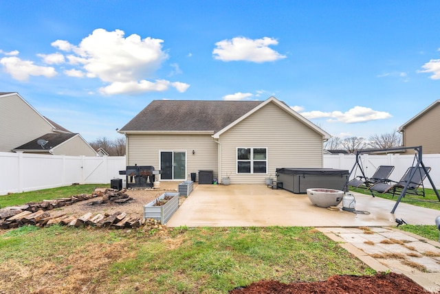 rear view of property featuring a yard, cooling unit, a patio, and a hot tub