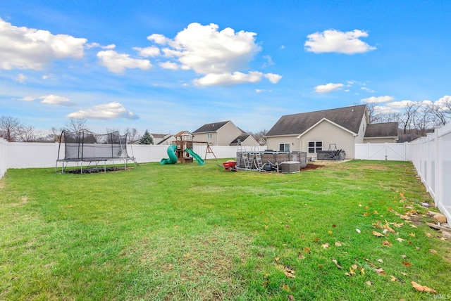 view of yard with a playground, a trampoline, and a swimming pool