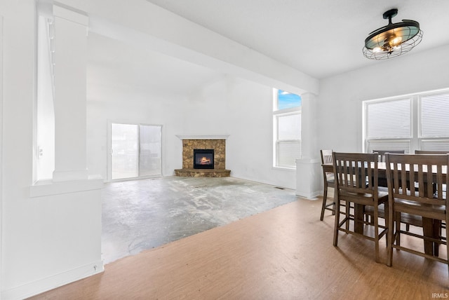 dining room with wood-type flooring and a stone fireplace