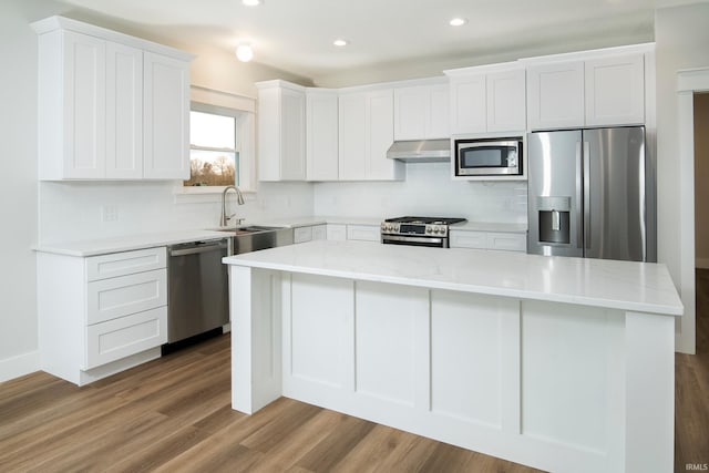 kitchen featuring white cabinetry, sink, hardwood / wood-style floors, a kitchen island, and appliances with stainless steel finishes