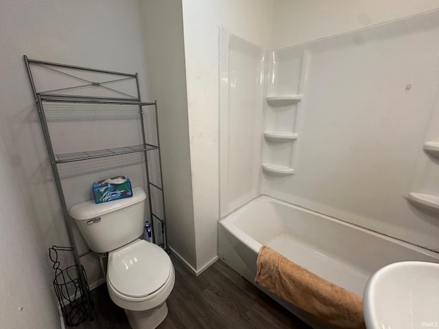 bathroom with toilet, hardwood / wood-style flooring, and bathing tub / shower combination