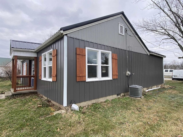 view of side of property featuring a lawn and central AC