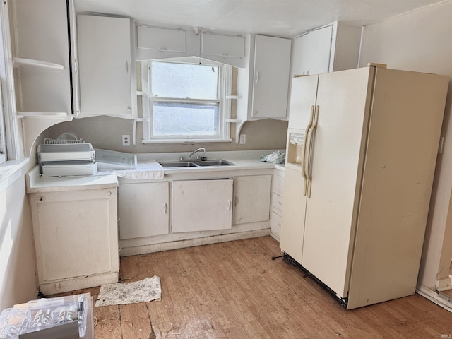 kitchen featuring white cabinets, light hardwood / wood-style flooring, white fridge with ice dispenser, and sink