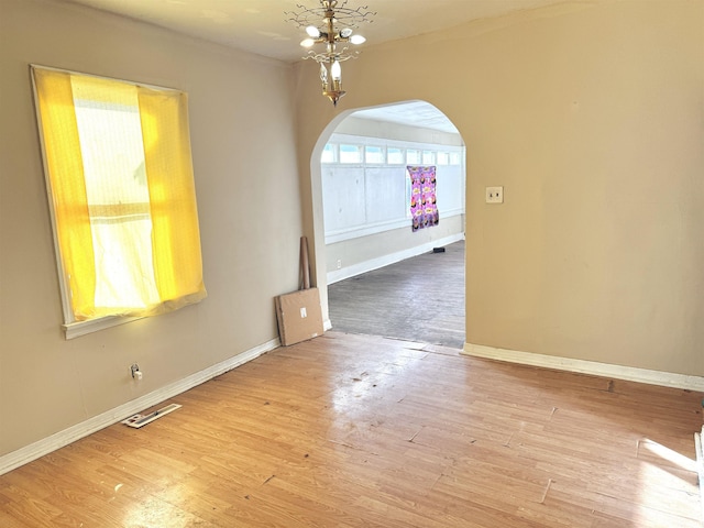 unfurnished room with hardwood / wood-style flooring and a chandelier